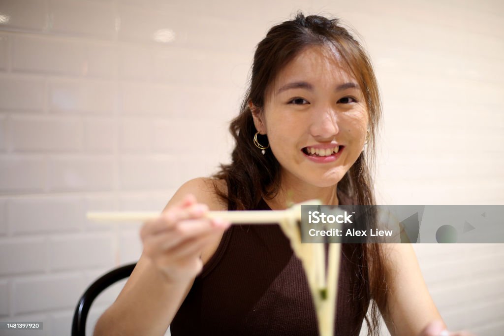 An Asian young woman is enjoying Japanese udon seaweed noodle in restaurant